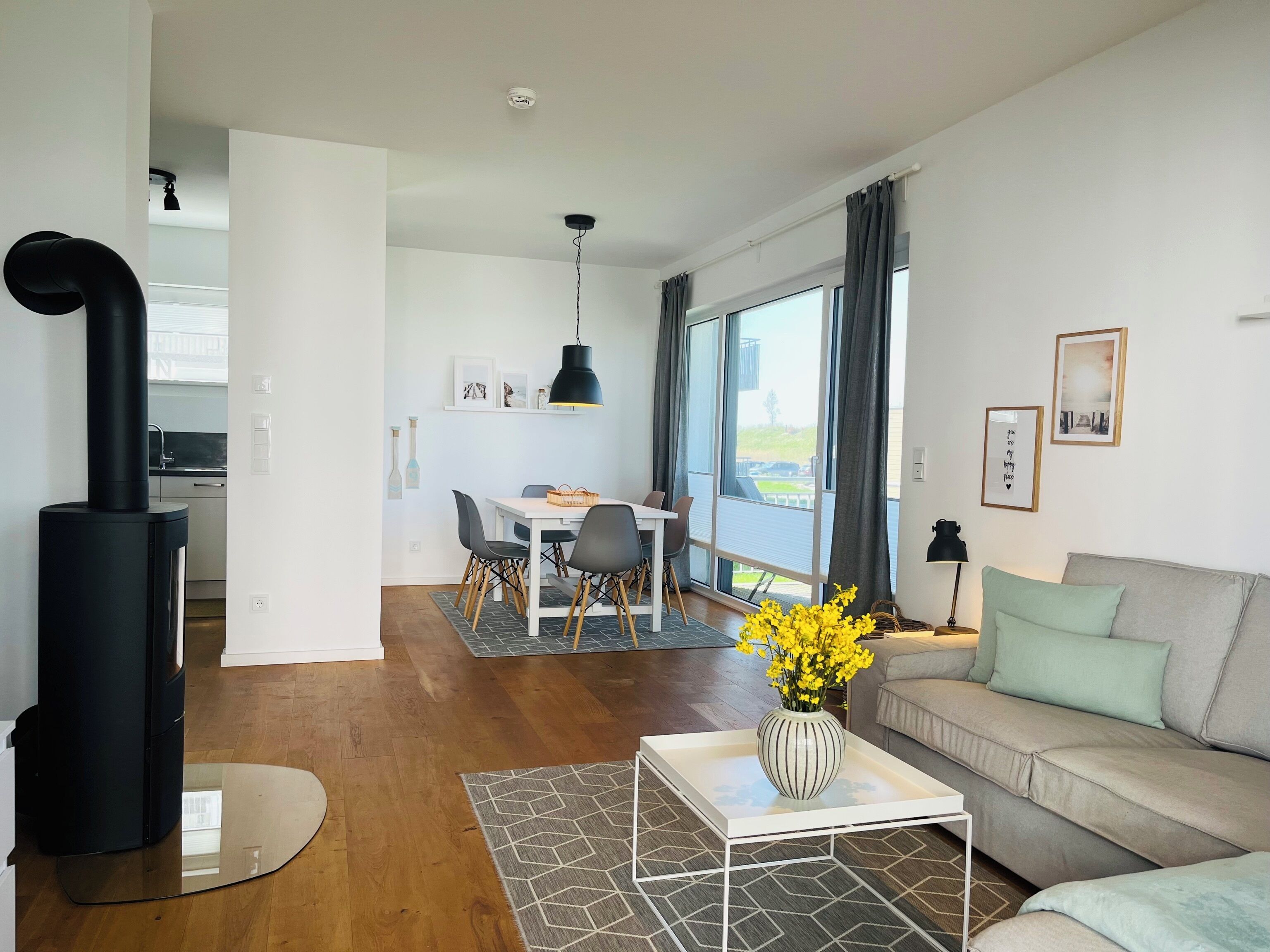 A modern living room with a sofa, a coffee table, and a dining area with chairs and a table.