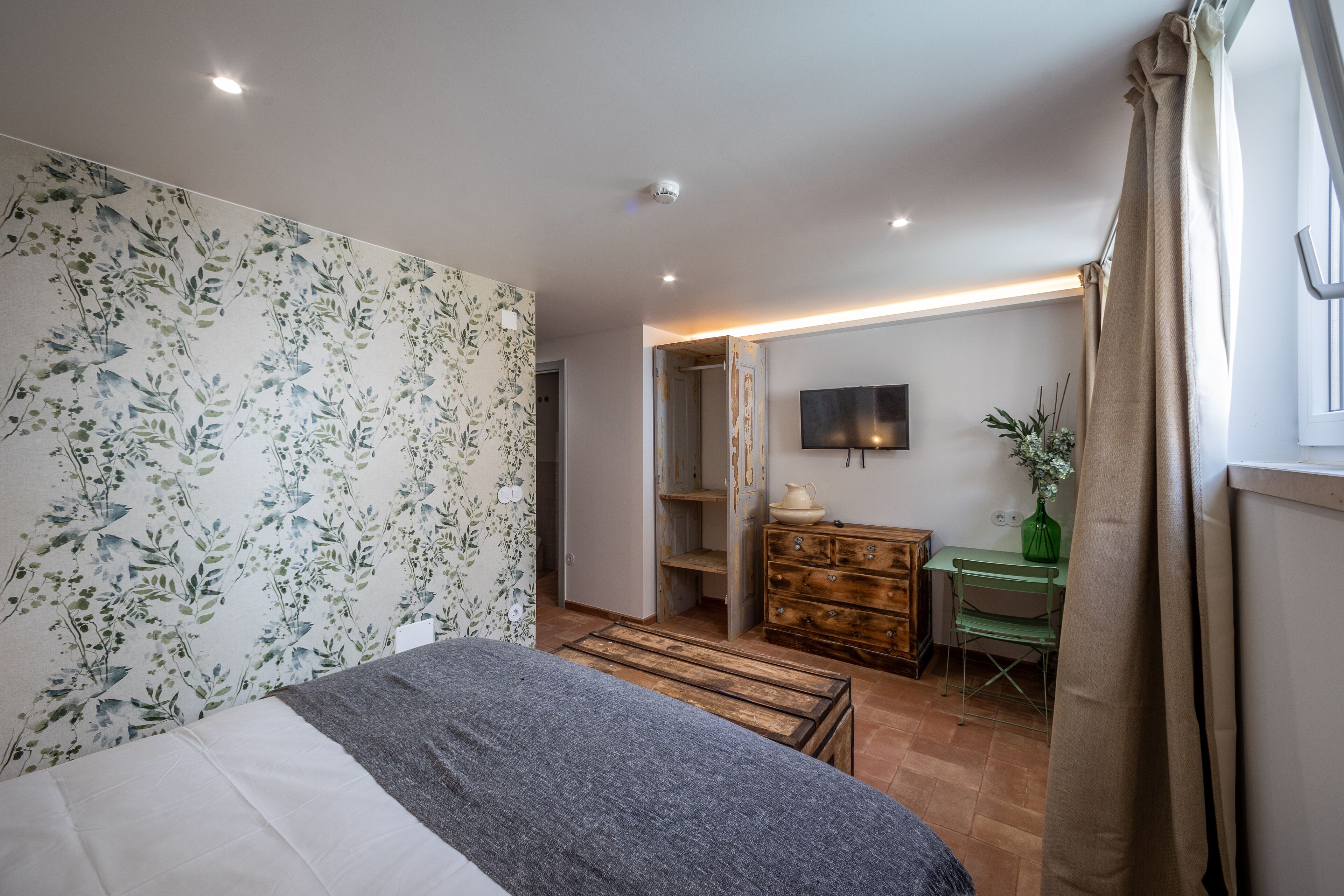 A bedroom with a bed, a dresser, a desk, and a chair.