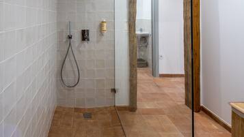Un baño moderno con paredes de azulejos blancos, una zona de ducha y un marco de puerta de madera.