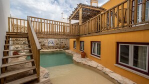 A wooden deck leading to a stone pool with a wooden staircase. - Villa Galega (Torres Vedras)