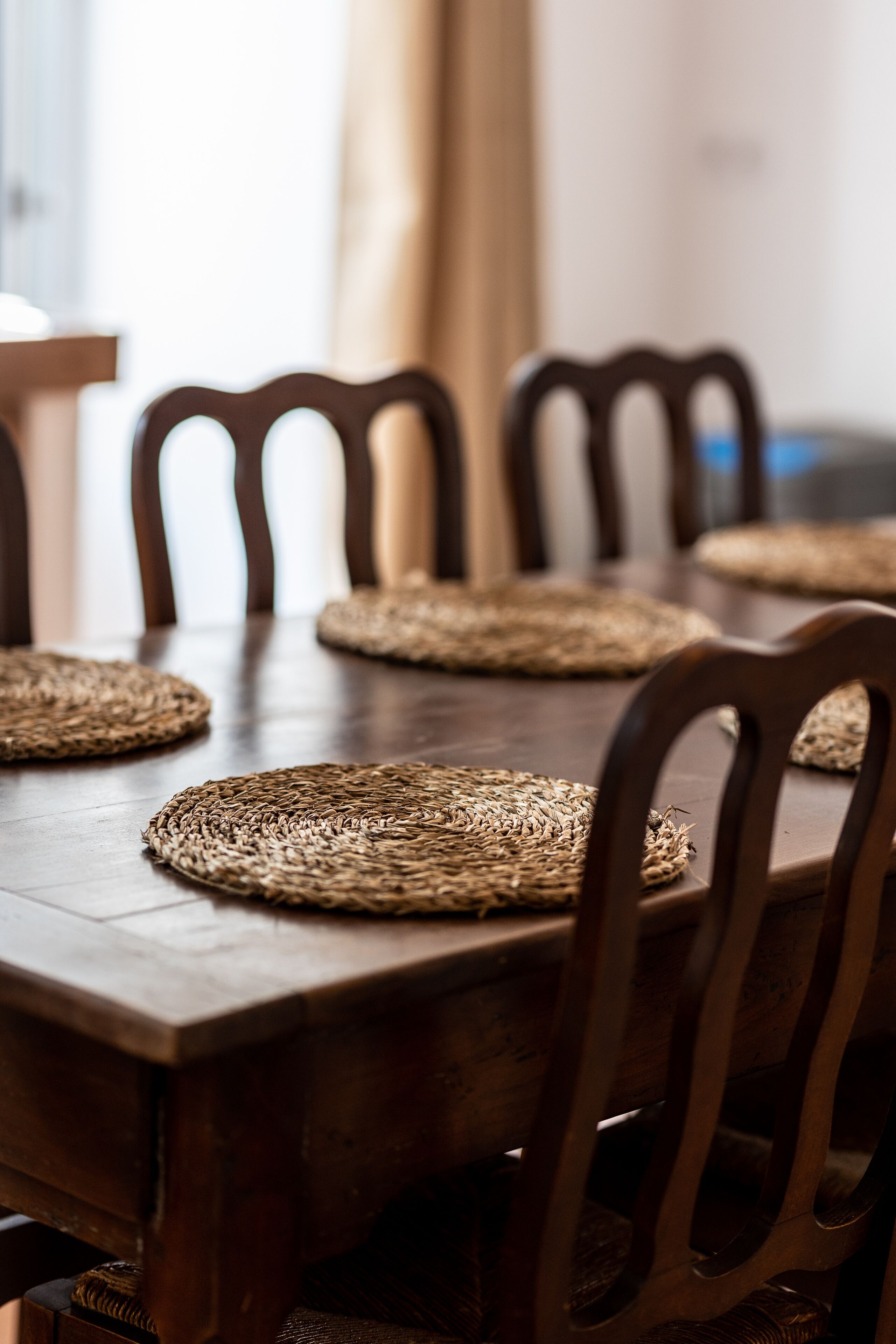 Una mesa de comedor de madera con individuales tejidos y sillas a juego.