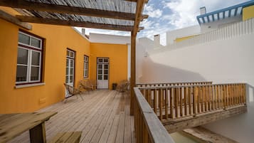 A wooden deck with a pergola, a small seating area with chairs, and a wooden railing.