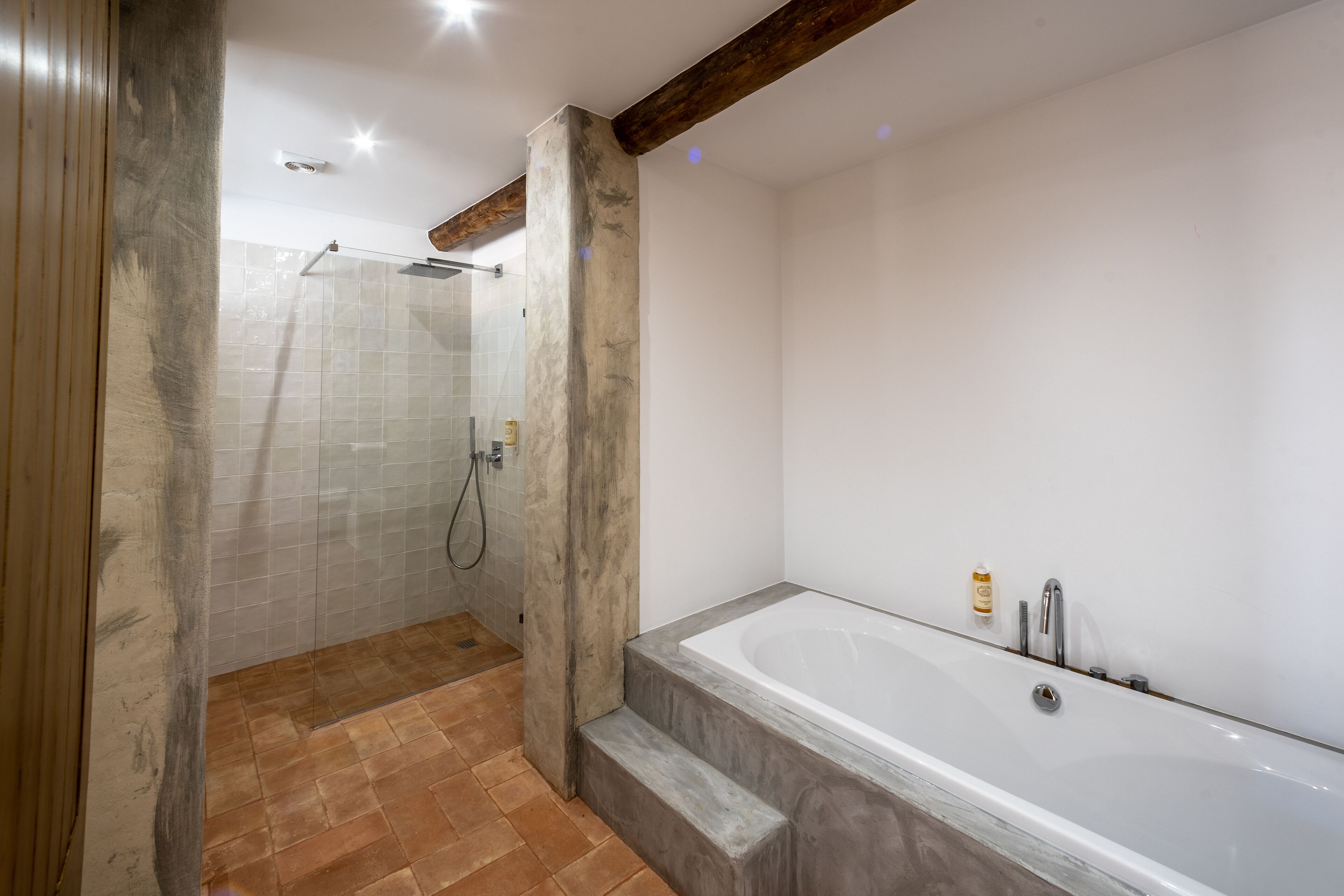 A modern bathroom with a bathtub, shower, and tiled floor.