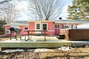 Ein rosafarbenes Haus mit Grill, Whirlpool und einer Holzterrasse.