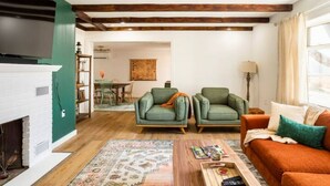 A living room with a fireplace, two green armchairs, a wooden coffee table, and a patterned rug. - Kin Cottage Accord (Accord)