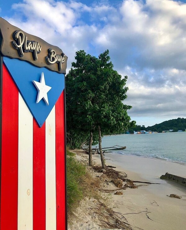A beach sign with 'Playa Buje' written on it, a star, and a flag design.