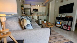 Un salon moderne avec un canapé gris, une table basse et un téléviseur posé sur un meuble.