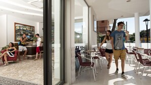 A modern interior with a bar area, seating, and a view of the outside. - Hotel Baltic (Rimini)