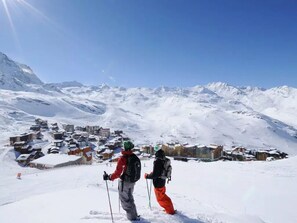 Un paysage de montagne enneigé, avec une station de ski en arrière-plan.