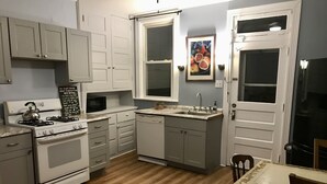 A kitchen with white cabinets, a stove, a microwave, a dishwasher, and a sink. - Eclectic Historic Sunny Vista Home with City Views, Northshore (Pittsburgh)