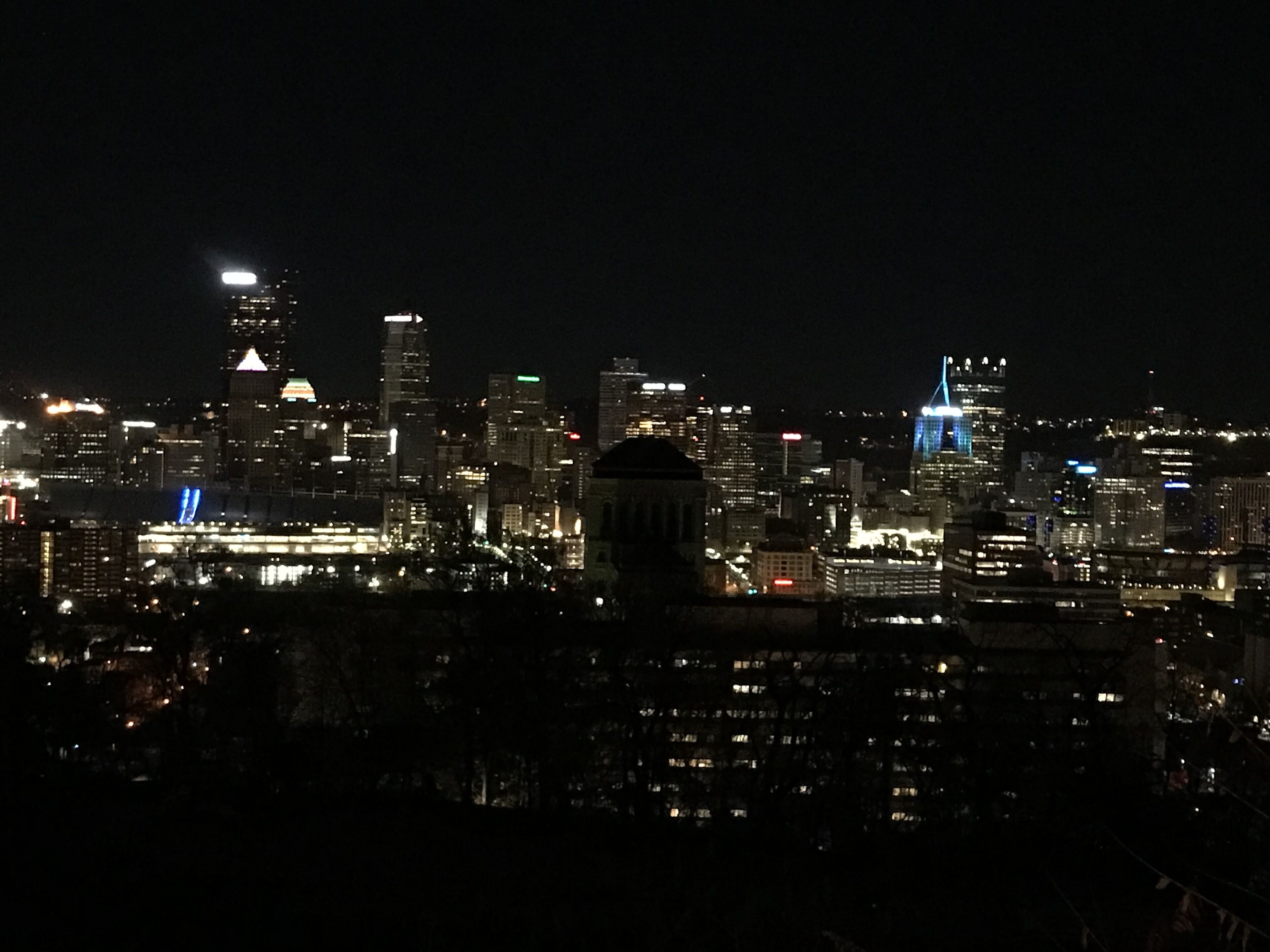 A nighttime cityscape with illuminated buildings and a prominent dome structure.