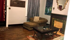 A living room with a fireplace, a sofa, a coffee table, and a painting on the wall. - Eclectic Historic Sunny Vista Home with City Views, Northshore (Pittsburgh)