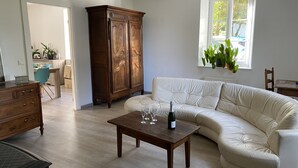 Un salon avec un canapé beige, un meuble en bois et une table sur laquelle se trouvent des verres à vin et une bouteille.