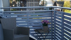 A balcony with a wicker chair, a small table with a potted plant, and a railing.