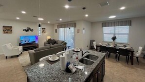 A modern living room with a TV, sofa, and dining area with a kitchen island.