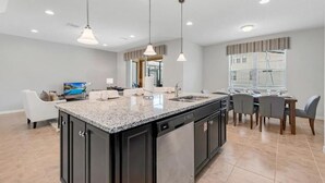 A modern kitchen with granite countertops, a central island, and a dining area with a table and chairs.