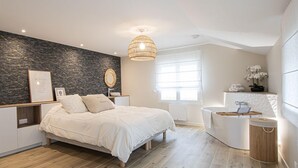 A modern bedroom with a bed, bedside tables, a built-in vanity, and a large window. - Feet in the sand (La Forêt-Fouesnant)
