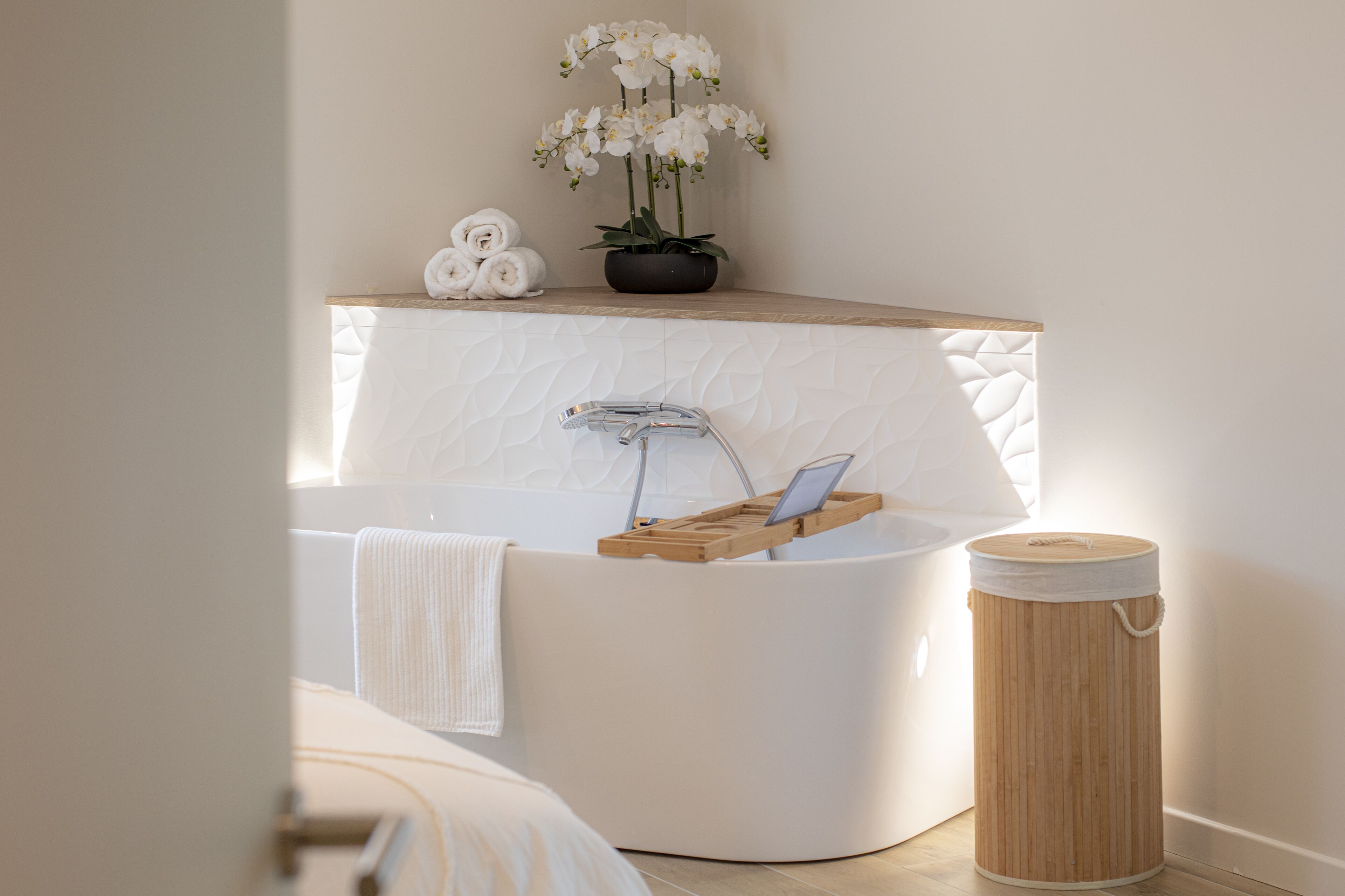 A modern bathroom with a freestanding bathtub, a wooden vanity, and a potted orchid plant.