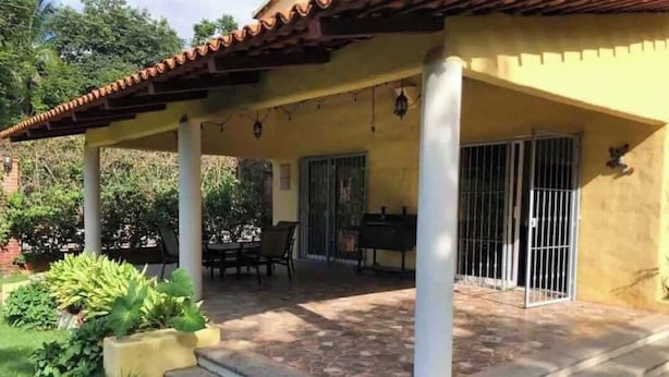 Un patio cubierto con una parrilla, mobiliario exterior y un jardín.
