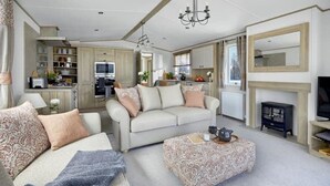 A spacious living room with a sofa set, a coffee table, and a fireplace. - Bluebell Lodge (South Cerney)