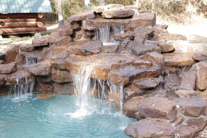 A natural rock formation with a cascading water feature. - Log Cabin With Trails/Pool/Game Room/Acreage/ Near Houston (Cleveland)