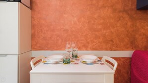 A small dining table with two plates, two wine glasses, and a water glass set on a tablecloth with a cartoon pattern. - Italianway Easy - Copernico 63 (Milan)