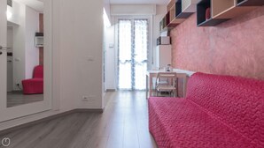 A modern living room with a red sofa, a dining table with chairs, and a kitchen area with cabinets. - Italianway Easy - Copernico 63 (Milan)
