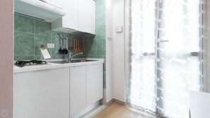 A kitchen with white cabinets, a gas stove, and a sink. There are wooden utensils hanging on the wall. - Italianway Easy - Copernico 63 (Milan)