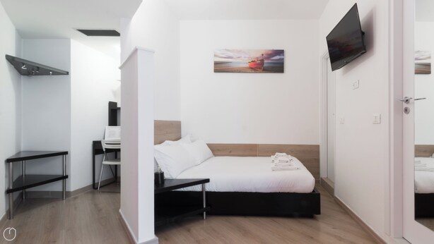 A modern bedroom with a bed, a desk, a chair, a flat-screen TV, and a painting on the wall. - Italianway Easy - Copernico 63 (Milan)
