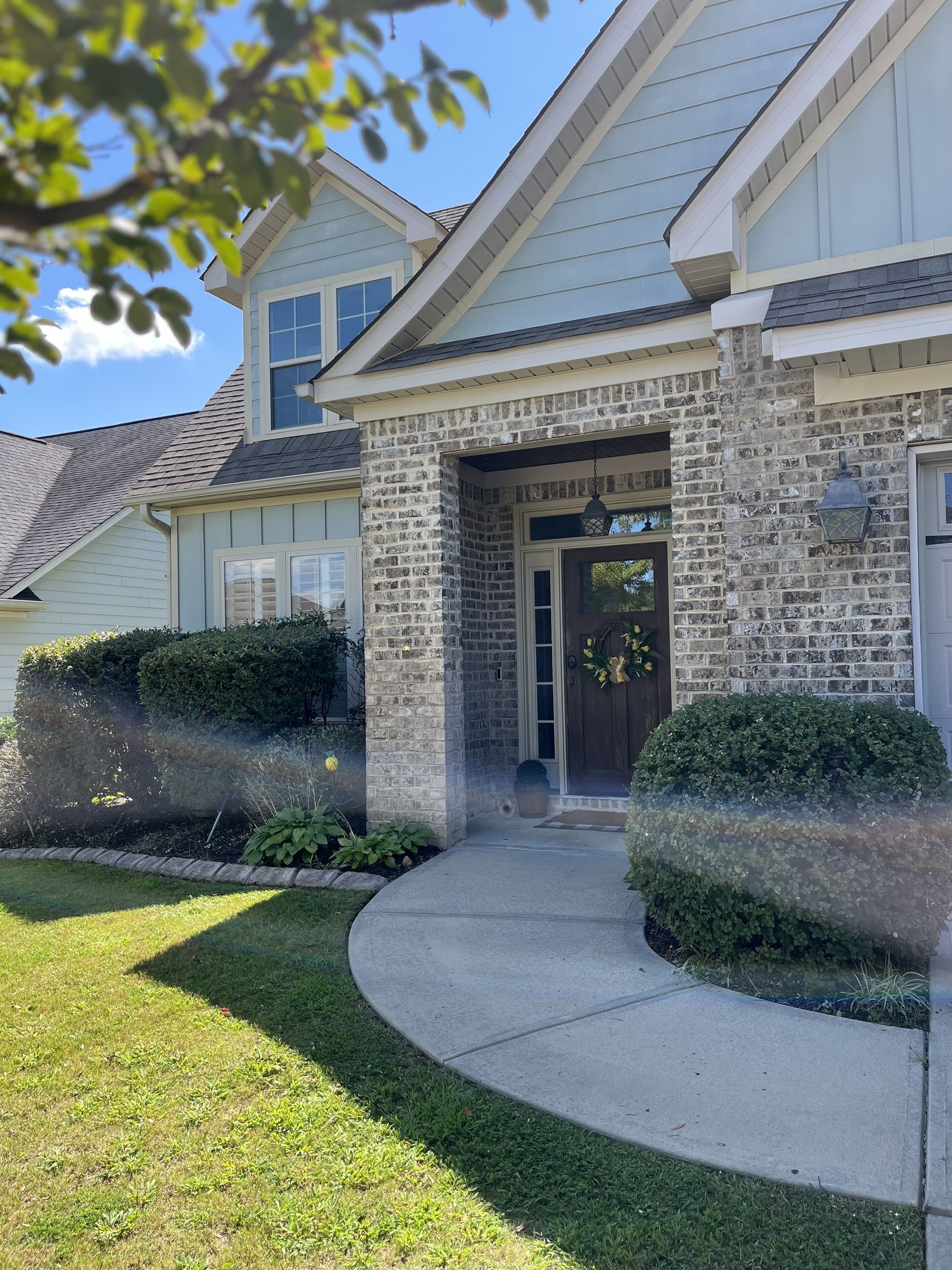 A two-story house with a brick facade, a front porch, and a well-maintained lawn.
