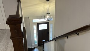 Una escalera de madera con barandilla, peldaños alfombrados y un candelabro.
