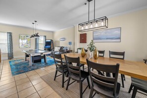 A dining area with a wooden table and chairs, a pool table, and a ceiling fan.