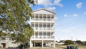 A multi-story building with balconies, a covered entrance, and a parking lot. - Ocean View Luxury Rental - Sleeps 16 (North Myrtle Beach)