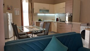 Une cuisine compacte comprenant une table à manger, des chaises, un lave-linge et un canapé bleu.