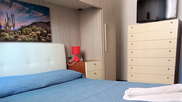 Une chambre d’hôtel avec un lit, une commode, un téléviseur et un tableau au mur.