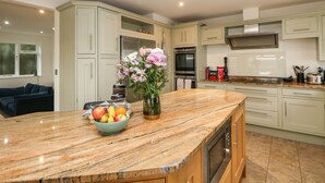 A modern kitchen with a marble countertop, built-in appliances, and light-colored cabinetry. - Glenhurst (Dronfield)