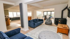 A spacious living area with a blue sofa, grey ottoman, and a fireplace. - Glenhurst (Dronfield)