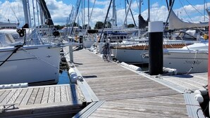 A marina with multiple docked sailboats, wooden walkways, and a clear blue sky. - Boat 'Floating House' with Lake View, Private Terrace and Wi-Fi (Kröslin)