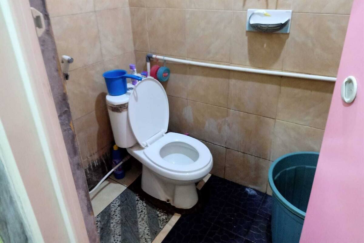 Ein kleines Badezimmer mit Toilette, Mülleimer und Ablage für Reinigungsmittel.