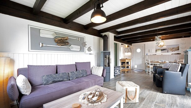 A modern living room with a purple sofa, wooden coffee table, and a dining area in the background.