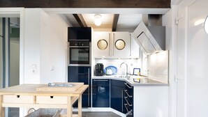 A modern kitchen with a wooden table, built-in appliances, and a dark blue cabinetry.
