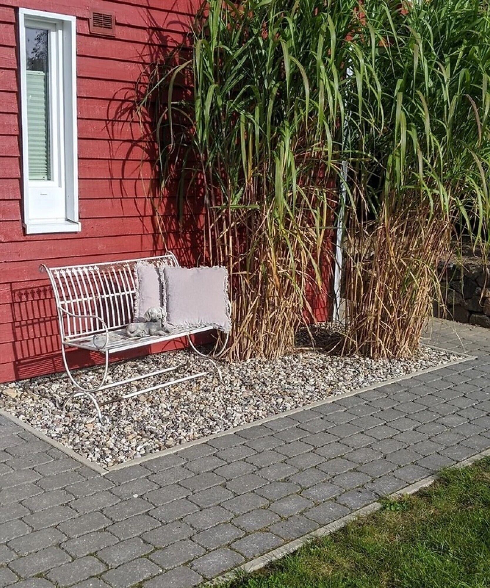 Un bâtiment rouge avec un banc blanc et un petit espace végétalisé.