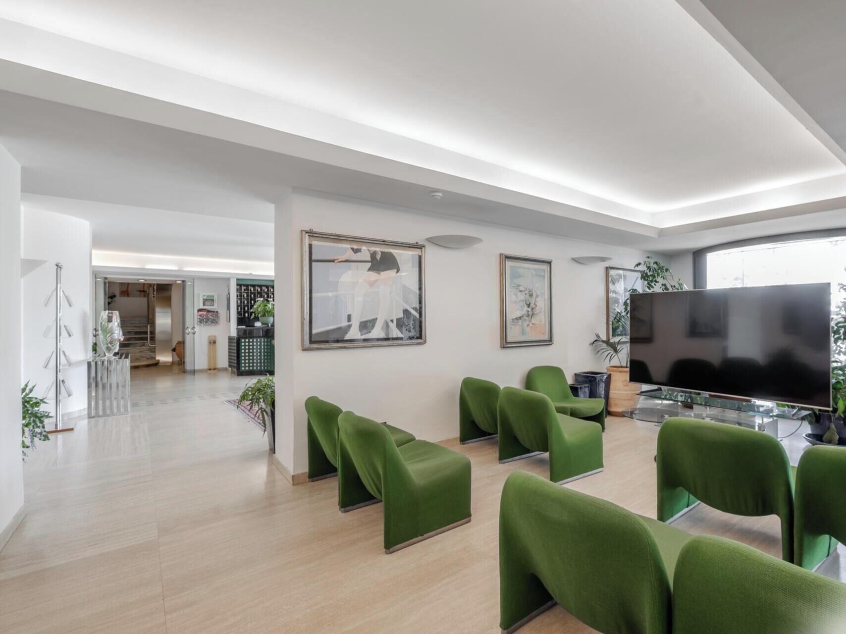 A modern interior with green upholstered seating, a flat-screen TV, and artwork on the walls.