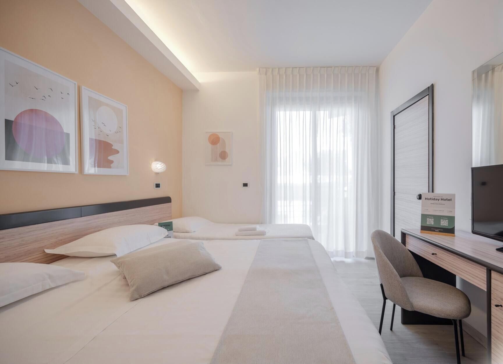 A hotel room with a bed, a desk, a chair, and a TV.