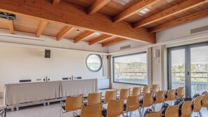 Un salón de conferencias con una larga mesa, sillas, un ventanal redondo y vistas al paisaje.