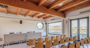 Uma sala de conferências com uma mesa comprida, cadeiras, uma janela redonda e vista para a paisagem.