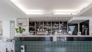 Una zona de bar con mostrador, estantes llenos de botellas y un cartel enmarcado arriba.