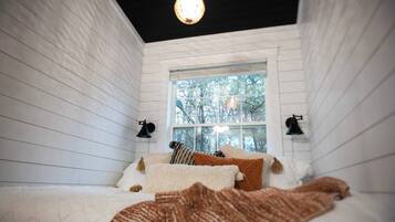 A cozy bedroom with a bed, pillows, and a window with a view of trees.