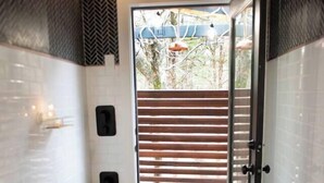 Une salle de bain moderne avec un plancher en bois, un banc et une petite table sur laquelle sont posés des articles de toilette.