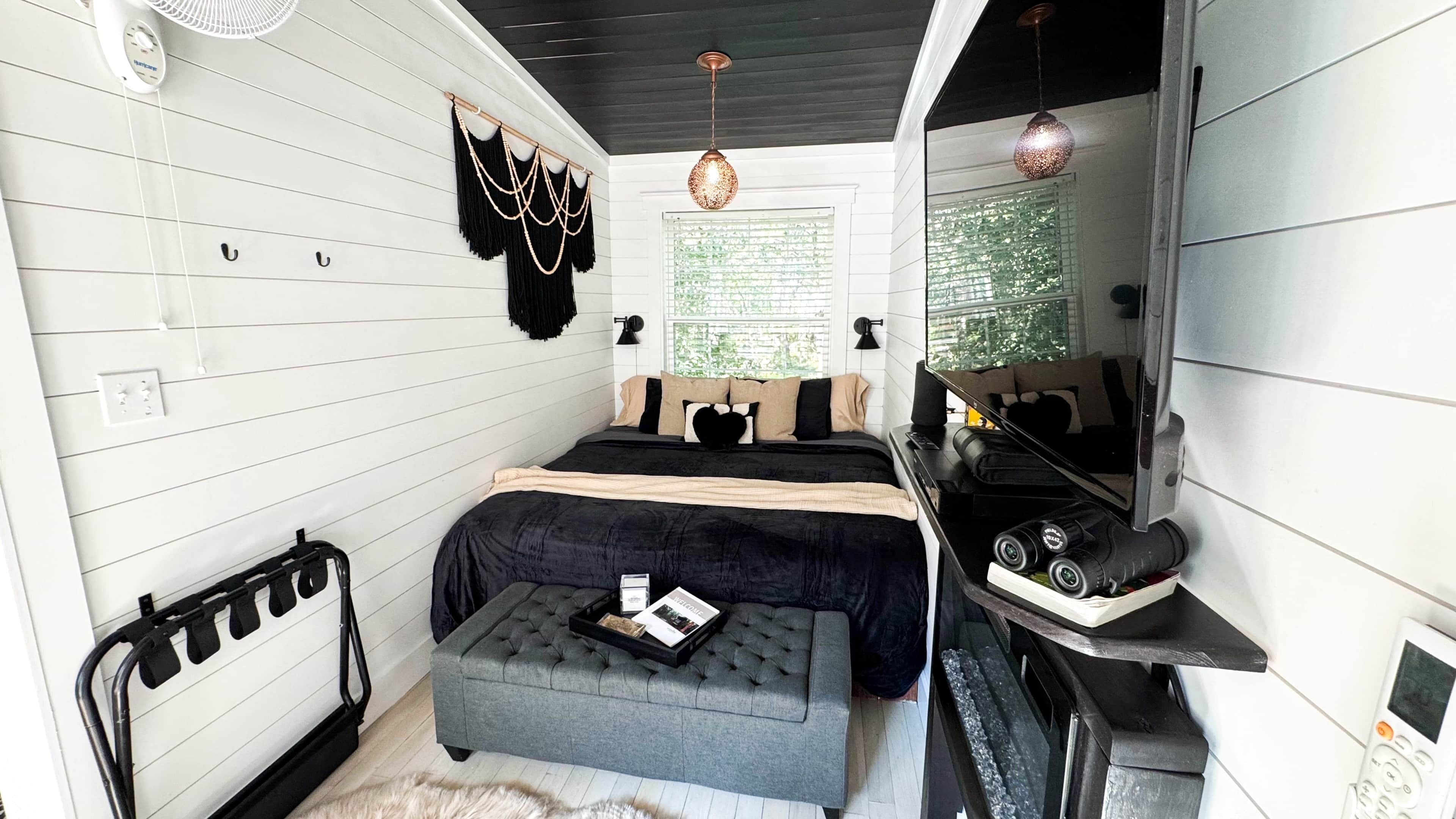 Habitación compacta con cama, mesita de noche y una pequeña zona de estar.